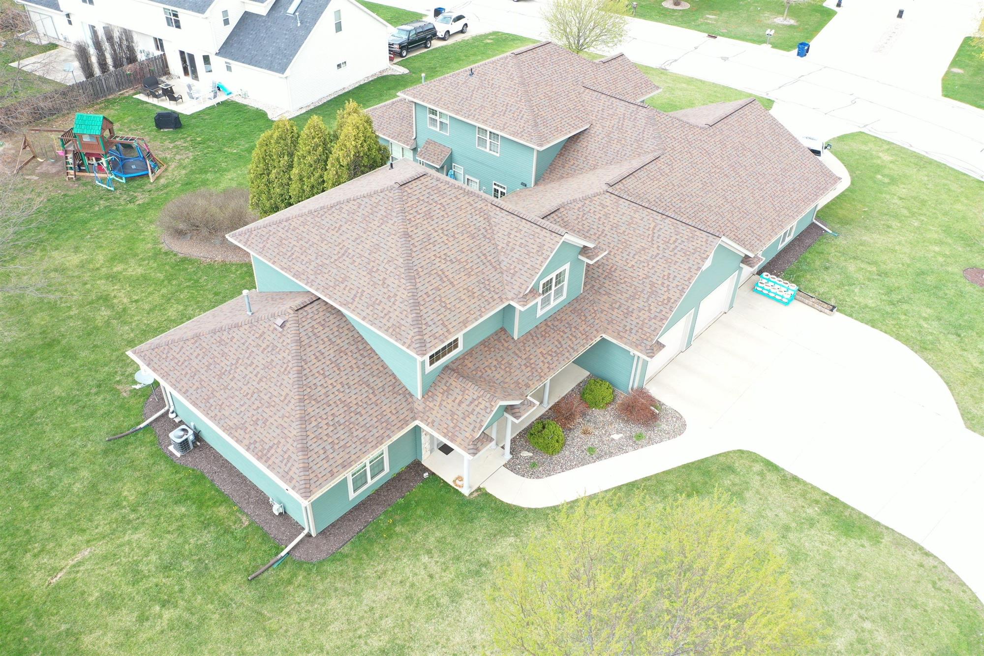 Large home with turquoise siding and a brown roof showing newly installed asphalt shingles in Green Bay, WI