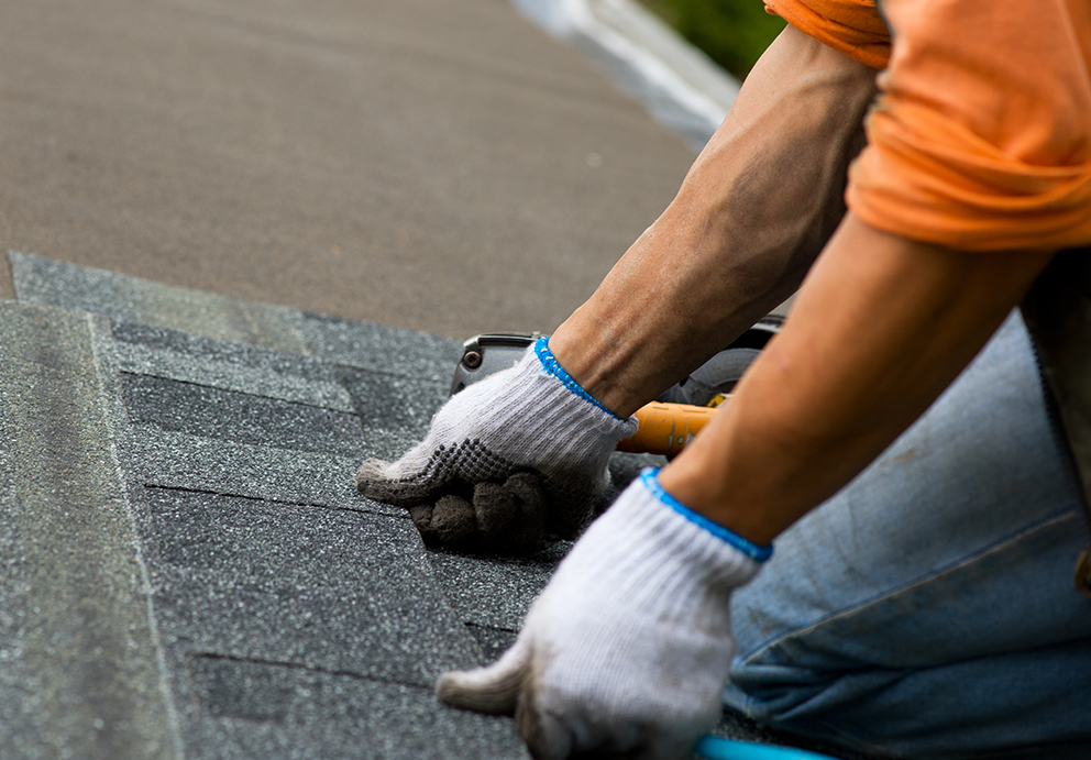 Roofing contractor in Grand Chute, WI repairing damaged asphalt shingles