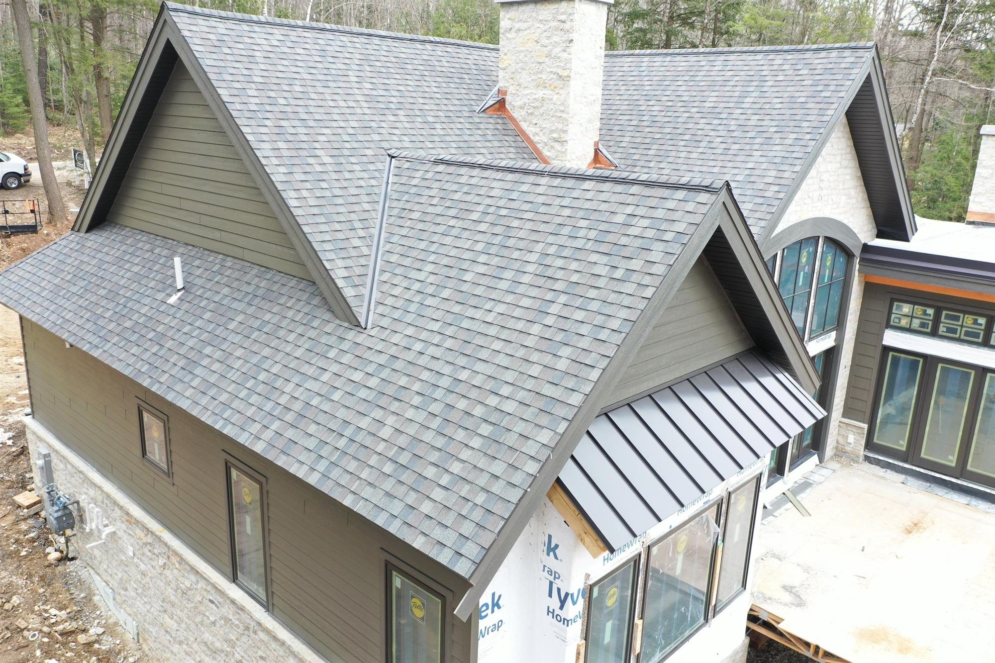 House in the Wood with new Asphalt Shingles installed by Overhead Solutions.