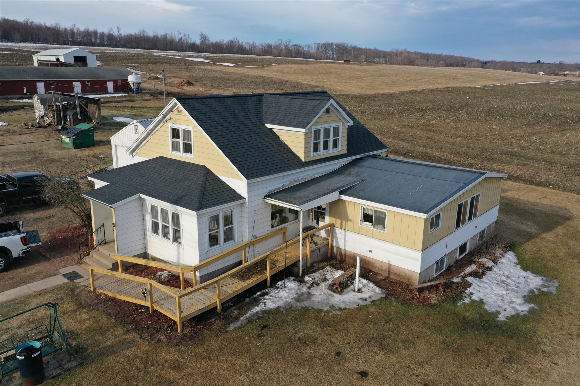 Country home with yellow siding and a dark roof newly installed by Overhead Solutions