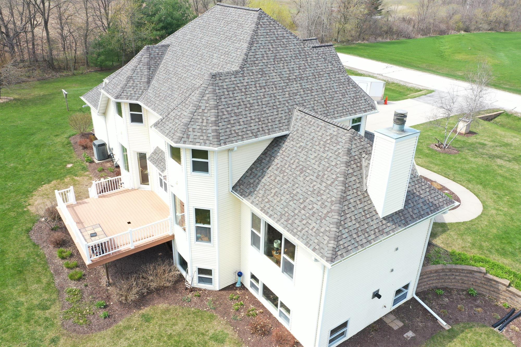 Large multi-story home with white siding and grey asphalt shingled roofing in Green Bay, WI