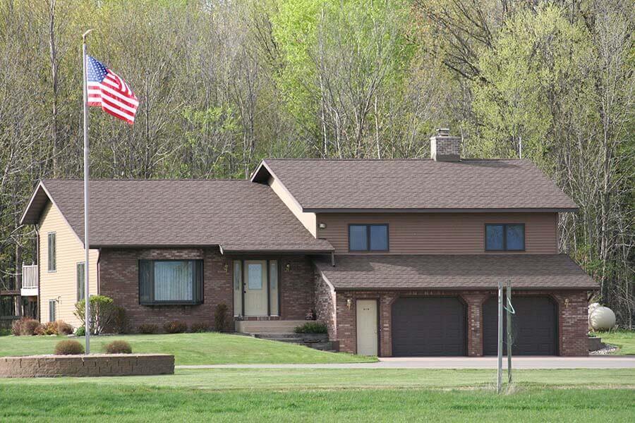 Brown multi-story home with matching siding and shingles installed by overhead solutions in Green Bay, WI. 